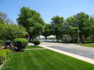 Suburban street with green grass and trees in background.